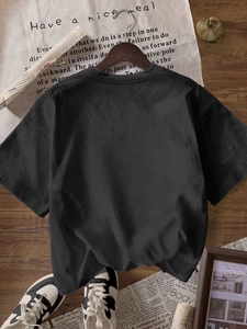 Back view of black loose crewneck cotton t-shirt for women in a vintage minimalist setting