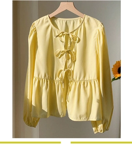 Détail de la blouse à rayures jaunes et blanches avec nœuds décoratifs et ourlet péplum