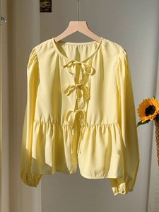 Détail de la blouse à manches longues à rayures jaunes avec trois nœuds papillon devant