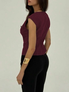 Elegant burgundy sleeveless slim-fit top paired with black trousers and gold bracelet
