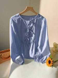 Détail du chemisier à rayures bleues avec nœuds de serrage et poignets élastiques