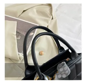 Detail of checkered quilted black tote bag featuring a decorative polka dot silk scarf handle