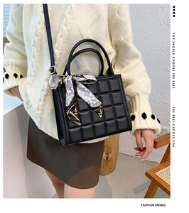 Close-up of black quilted tote bag with decorative patterned silk scarf and slim strap