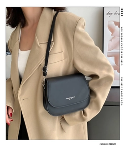 Détail du sac à bandoulière minimaliste en cuir noir avec lettrage blanc fashion