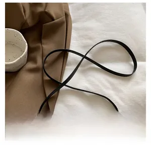 Détail de la fine bandoulière en cuir noir avec des ferrures à la finition mate