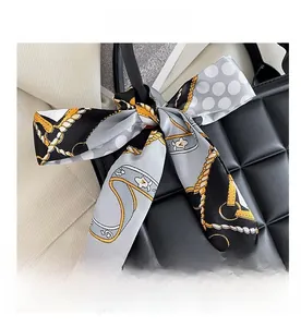 Close-up of silk-textured ribbon with gold chain pattern on black quilted handbag handle