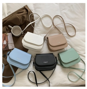 Mise à plat de sacs besaces minimalistes en cuir en cinq couleurs pastel avec finitions argent