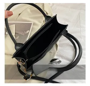 Detail of black tote bag interior with zipper compartment and silk scarf handle decor