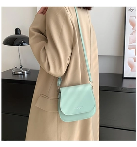 Gros plan d'un sac bandoulière vert menthe en cuir PU avec rabat arrondi et texte blanc