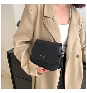 Gros plan d'un sac besace noir mat avec logo blanc et boucles métalliques argentées