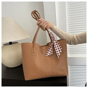 Close-up of brown tote bag with smooth texture and decorative checkered silk scarf