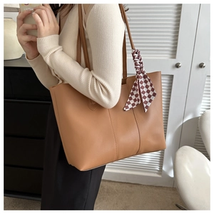 Close-up of caramel brown tote bag featuring a checkerboard silk scarf on handle