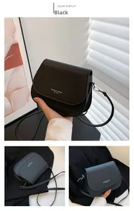 Détail du sac bandoulière en cuir noir avec sangle réglable et lettrage sur le devant