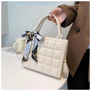 Detail of cream quilted tote bag with checkered pattern and elegant silk scarf handle