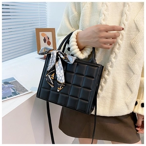 Detail of black quilted PU leather tote bag with silk scarf and crossbody strap