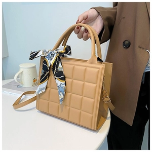 Close-up of camel quilted tote bag featuring a decorative silk scarf and adjustable strap