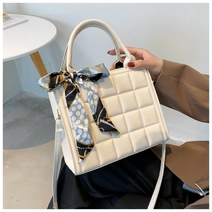 Detail of cream quilted tote bag featuring a decorative printed silk scarf on handle