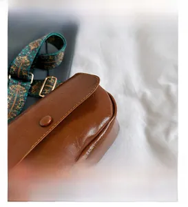 Detail of vintage brown PU saddle bag showing fine stitching and ethnic strap