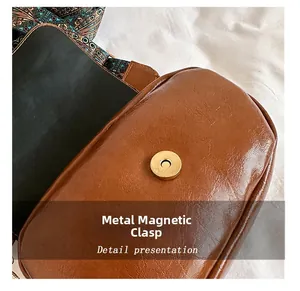 Detail of the golden hardware magnetic snap and ethnic woven strap on brown leather bag