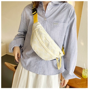 Detail der cremeweißen gewebten Brusttasche mit gelbem Gurt an einem Model
