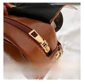 Detailed close-up of a smooth gold metal zipper on a dark brown textured PU leather bag
