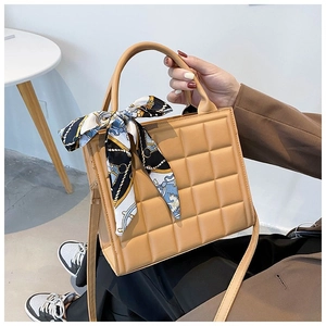 Detail of checkered embossed tote bag with elegant silk scarf wrapped around handle