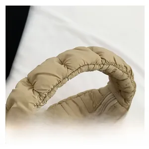 Detail of padded handle and smooth metal zipper on khaki quilted cloud handbag
