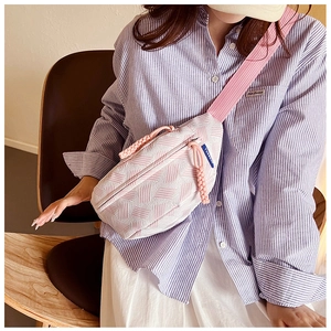 Detalle de bolso bandolera tejido en rosa y blanco con rayas y correa ancha