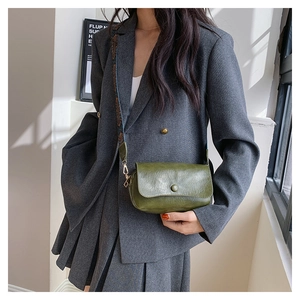 Detail view of dark green textured PU leather crossbody bag with patterned wide strap