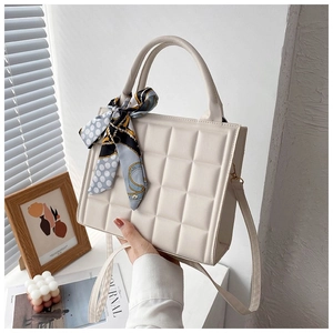 Detail of cream checkered tote bag with patterned scarf detail and slim shoulder strap