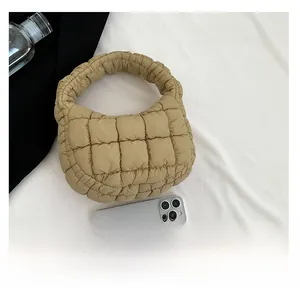 Detail of beige quilted puffer bucket bag featuring puffy texture and a soft integrated handle