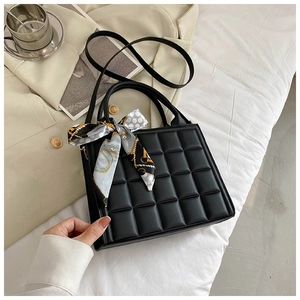 Close-up of black quilted tote bag with floral silk scarf detail and crossbody strap