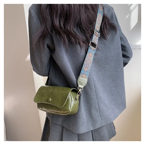 Dark green leather saddle bag featuring a wide bohemian style printed shoulder strap