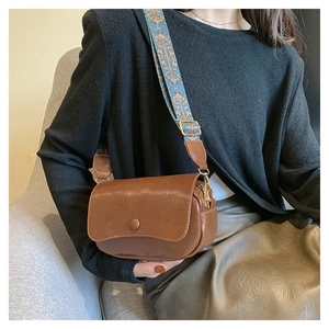 Detail of a brown PU saddle bag with a wide bohemian patterned woven strap