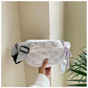 Detalle de bolso bandolera lila con textura geométrica en relieve y colgante trenzado