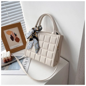 Close-up of cream quilted tote bag with a silk scarf tied to the handle and a slim strap