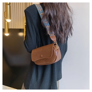 Brown PU saddle bag with ethnic pattern wide shoulder strap shown on model's side view