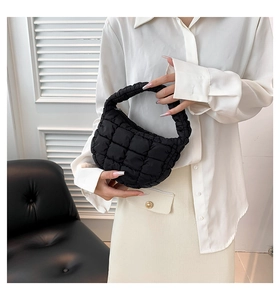 Macro view of black quilted puff bag showing soft checkered padding and handle detail