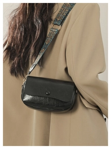 Detail of black vintage PU leather saddle bag with ethnic patterned wide shoulder strap