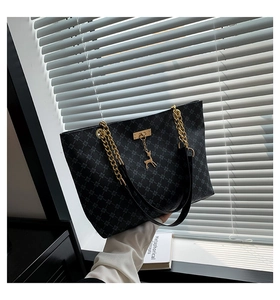 Close-up of black geometric pattern tote bag with golden chain and deer charm detail