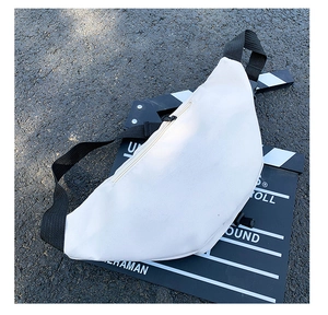 Détail du sac banane en tissu Oxford crème avec sangle noire sur surface d'asphalte