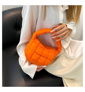 Close-up of orange quilted cloud handbag with ruched texture and zipper detail