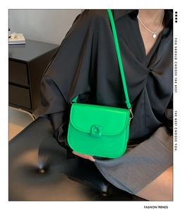 Model wearing a bright green crossbody saddle bag with half-round flap and square buckle