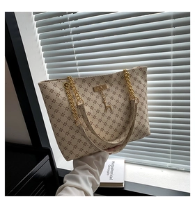 Detail of vintage monogram tote bag with gold chain strap and deer pendant on model