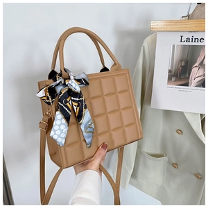 Detail of checkered quilted tote bag in khaki with twisted silk scarf on handles