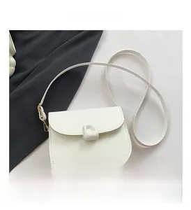 Detail of white PU saddle bag featuring a unique organic-shaped buckle and gold hardware