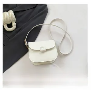 Top view of a white PU saddle bag with decorative buckle next to a phone for size scaling