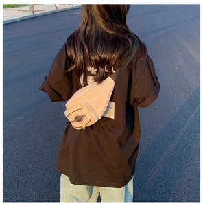 Photo en extérieur d'un sac banane rose clair en tissu Oxford porté par un mannequin