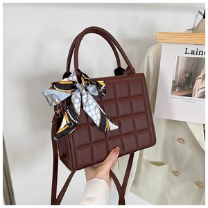 Detail of dark brown checkered tote bag featuring a decorative silk scarf on the handle