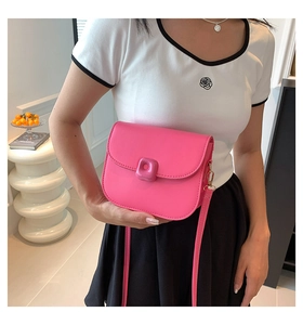 Detail of bright pink crossbody saddle bag with glossy finish and matching buckle detail